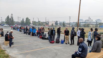 Personas sin vehículo hacen cola en Yellowknife, Canadá, para registrarse en un vuelo para dirigirse al territorio canadiense de Calgary, el jueves.
