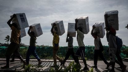 Unos voluntarios llevan urnas de cartón a los colegios electorales en Asmat, al sur de la provincia indonesia de Papúa, el 13 de febrero.