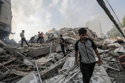 Varios palestinos entre los escombros de un edificio derrumbado tras un ataque israelí, este domingo en Gaza. 