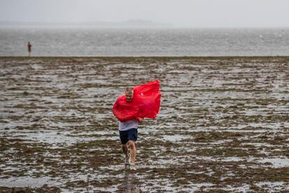 Un hombre camina sobre en la bahía de Tampa, donde el nivel del agua ha bajado como consecuencia de la dirección de los vientos del huracán.
