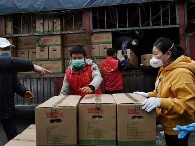 Un grupo de voluntarios descarga alimentos para un complejo de viviendas en Wuhan, el foco de la epidemia de coronavirus.