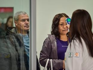 Personal sanitario toma la temperatura a los viajeros en el aeropuerto de Ciudad de México.