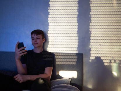 Un adolescente usa su 'smartphone' en su habitación.