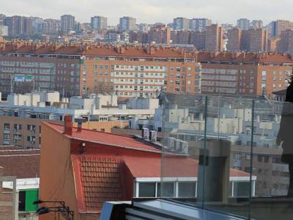 Las viviendas pueblan el horizonte de fondo mientras la silueta de una mujer se dibuja en un balcón.