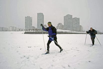 Dos hombres aprovechan la fuerte nevada en el parque de Salburua de Vitoria para practicar esquí de fondo.