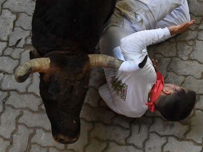 A participant is struck by a bull during the "encierro" (bull-run) of the San Fermin festival in Pamplona, northern Spain on July 12, 2022. - On each day of the festival six bulls are released at 8:00 a.m. (0600 GMT) to run from their corral through the narrow, cobbled streets of the old town over an 850-meter (yard) course. Ahead of them are the runners, who try to stay close to the bulls without falling over or being gored. (Photo by MIGUEL RIOPA / AFP)