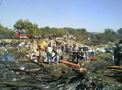 Bomberos y trabajadores de los servicios de emergencia en el lugar donde se estrelló el avión de Spanair.