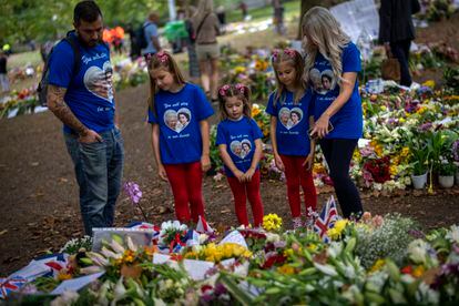 Jamie y Emma y sus hijas miraban el lunes las flores y mensajes colocados para la reina Isabel II en el memorial de Green Park, junto al palacio de Buckingham en Londres.