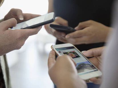 Un grupo de adolescentes usa sus teléfonos móviles.