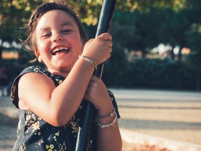 Una niña sonríe mientras se columpia en un parque.