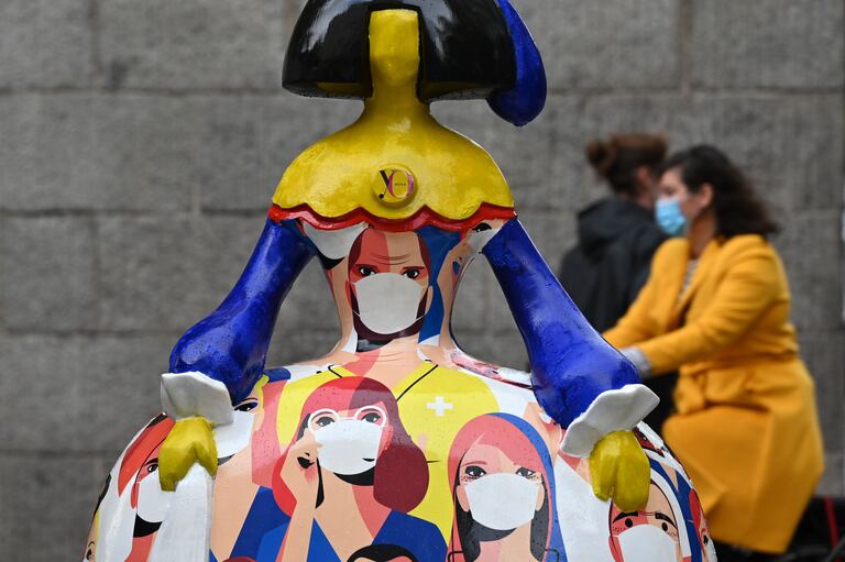 Varias personas pasan junto a una 'menina', decorada con sanitarios con mascarilla, este viernes en Madrid.