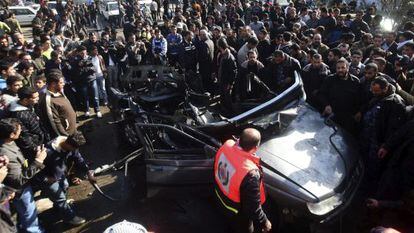 Decenas de palestinos se reúnen junto a los restos de un vehículo calcinado tras el impacto de un cohete del Ejército israelí, hoy en Gaza