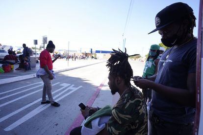 Jean Adler Cactus, un migrante haitiano que busca asilo en Estados Unidos, peina el cabello de otro migrante cerca de una entrada al cruce fronterizo este lunes, en Tijuana, México.