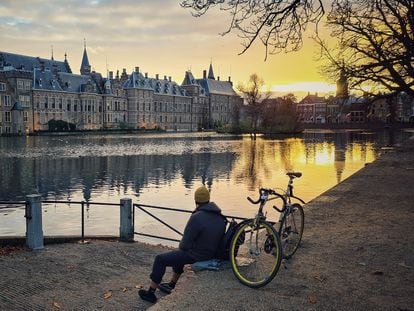 Un ciclista se toma un respiro mientras contempla el lago de Hofvjiver y el complejo de edificios políticos de Binnenhof durante un atardecer en La Haya.