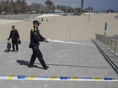 Un agente de la Guardia Urbana de Barcelona cierra un acceso en la playa.
