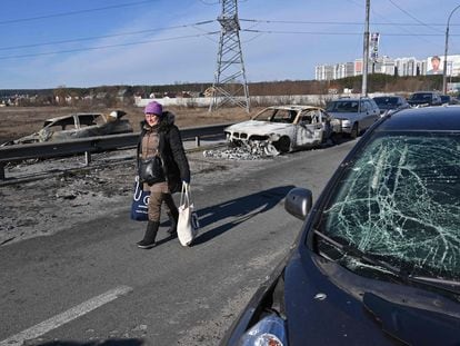Una mujer camina una zona con coches destrozados en Irpin, al norte de Kiev, la capital ucrania, este sábado 12 de marzo.