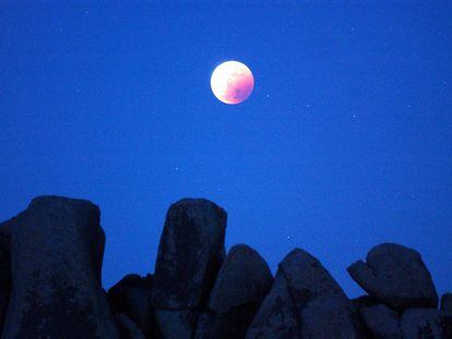 Una luna totalmente eclipsada brilla sobre formaciones rocosas en el desierto del Parque Nacional Joshua Tree, en California, EEUU, el 15 de mayo de 2003.