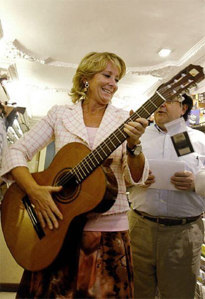 Esperanza Aguirre coge una guitarra durante su visita a un centro comercial de Lleida, donde ha ido a pedir el <i>no</i> al Estatuto catalán.