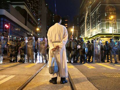 Un sacerdote frente a una fila de policías antidisturbios durante una protesta en Hong Kong este domingo.