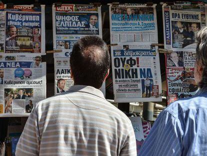 Dos hombres miran los titulares de la prensa griega.