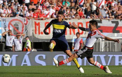 Cristian Pavon (izquierda), del Boca Junior, golpea el balón frente al defensa del River Plate Luis Olivera.