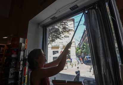 Una empleada de una librería de Madrid cierra las cortinas del escaparate, este martes.