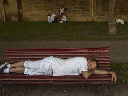 Un hombre duerme en un banco de Pamplona durante el primer día de San Fermín. En vídeo, 24 horas en los sanfermines