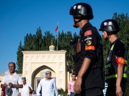 Unos policías chinos vigilan la salida de unos uigures de una mezquita, en 2017 en Kashgar.