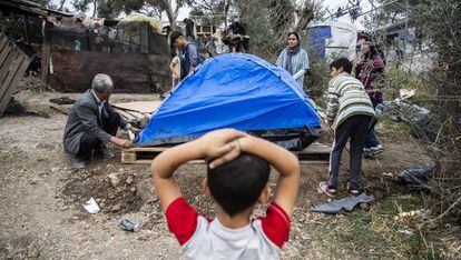 Un niño observa a varios miembros de su familia instalando su tienda de campaña en el campo de refugiados de Moria, en Lesbos (Grecia).