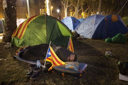 Més de 200 persones han passat la nit acampades davant de la seu del Tribunal Superior de Justícia de Catalunya (TSJC), a Barcelona. A la imatge, un home dorm al ras entre tendes de campanya.