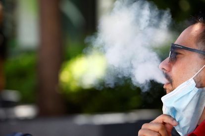 Un hombre expulsa el humo del tabaco mientras fuma sentado en una calle en Córdoba.