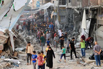 Grupos de palestinos caminan entre los escombros de un edificio destruido en el centro de Jan Yunis, fuertemente bombardeado por Israel durante la madrugada del lunes al martes. 