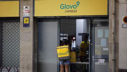 Un rider de Glovo frente a un supermercado express de la compañía de reparto a domicilio en Barcelona, en 2021.