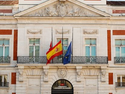 Las banderas madrileña, española y de la UE ondean a media asta en la fachada de la Real Casa de Correos, sede del Gobierno regional.