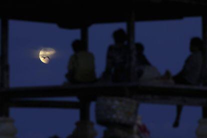 Un grup de persones contemplen l'eclipsi que es produeix quan el Sol, la Terra i la Lluna s'alineen de manera que la Lluna passa a través de l'ombra de la Terra, a Denpasar, Bali (Indonèsia).