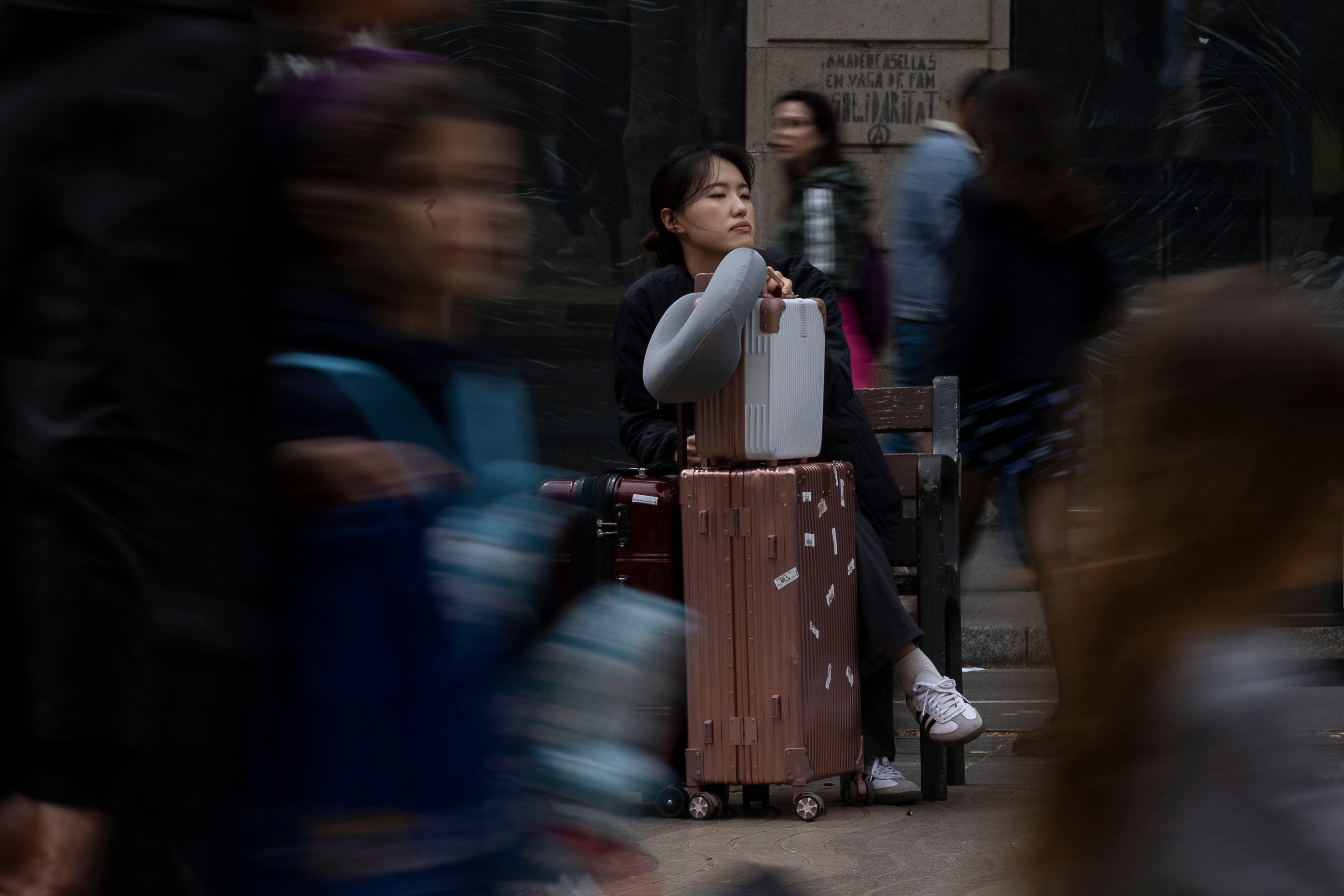 Una turista asiática descansa en un banco de la Rambla, este sábado en Barcelona.