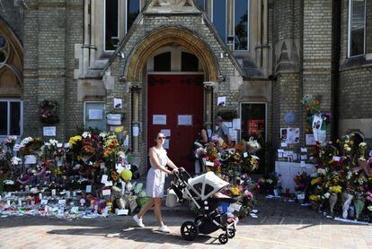 Una mujer con su bebé pasa este domingo junto a una zona de homenaje a las víctimas del incendio de la torre Grenfell, en North Kensington.