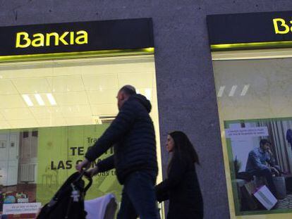 Una familia pasando por delante de una oficina de Bankia