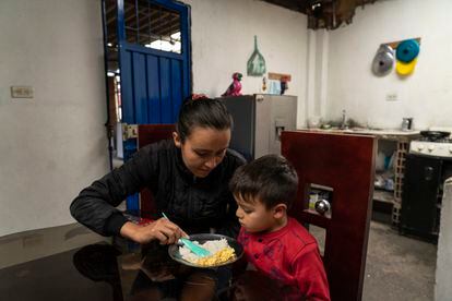 Andrea Usma, acompaña a su hijo Erick Albino, de cuatro años, a la hora de la cena en el barrio de Patio Bonito al sur de Bogotá. 