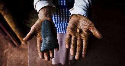 Una mujer marroquí muestra una semilla de argán en una mano y la piedra con la que muele en la otra.