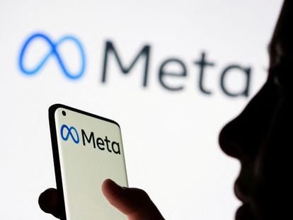 FILE PHOTO: Woman holds smartphone with Meta logo in front of a displayed Facebook's new rebrand logo Meta in this illustration picture taken October 28, 2021. REUTERS/Dado Ruvic/Illustration/File Photo
