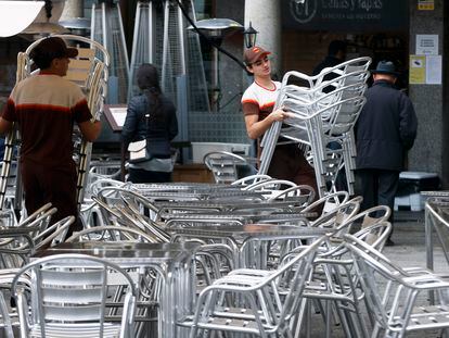 Varios trabajadores preparan las mesas de una terraza en un bar de Toledo.