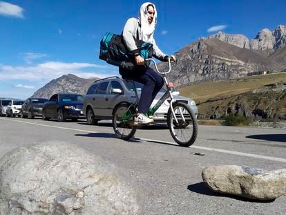 Dos hombres en bicicleta y una caravana de coches cruzaban la frontera de Rusia con Georgia para evitar la movilización, en septiembre.