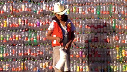 Un niño, frente a una pared de botellas de plástico en tetela, México.
