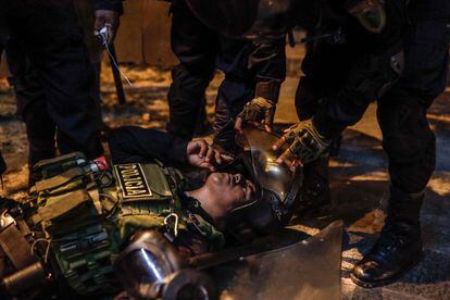 Policías ayudan a uno de sus compañeros durante los enfrentamientos con los manifestantes, afuera del Palacio de Justicia, en Lima. Desde que entró en vigor el estado de emergencia, este miércoles, han muerto 6 personas. 