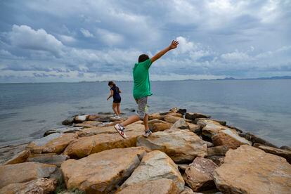  Unos niños saltan entre las piedras en la playa de la Curva, este miércoles.