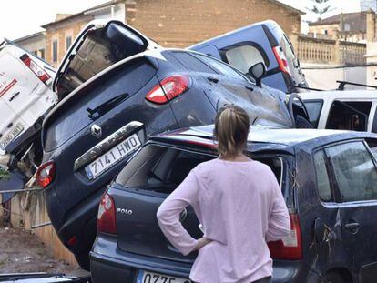 FOTO: Una dona, davant de diversos cotxes amuntegats a Sant Llorenç des Cardassar. VÍDEO: Així van captar els testimonis els aiguats.
