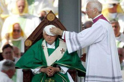 Benedicto XVI es atendido por Piero Marini, maestro de las celebraciones litúrgicas del Papa.