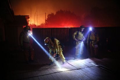 Un grupo de bomberos trabaja para salvar un hogar del incendio en Bonsall, cerca de Los Ángeles. 

