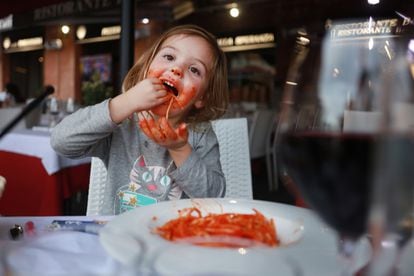 Una niña come pasta en un restaurante en Siena (Italia).